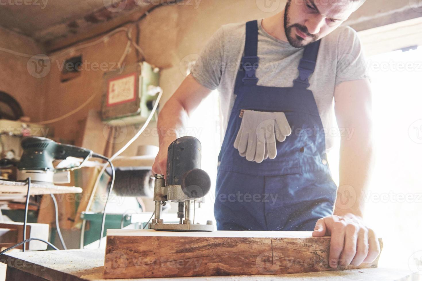 Portrait of a carpenter in working clothes in the workshop of the joiner's shop. photo