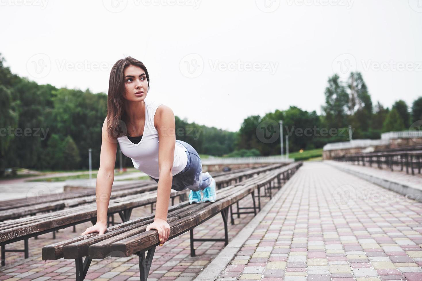 A beautiful athlete brunette performs outdoor exercises photo