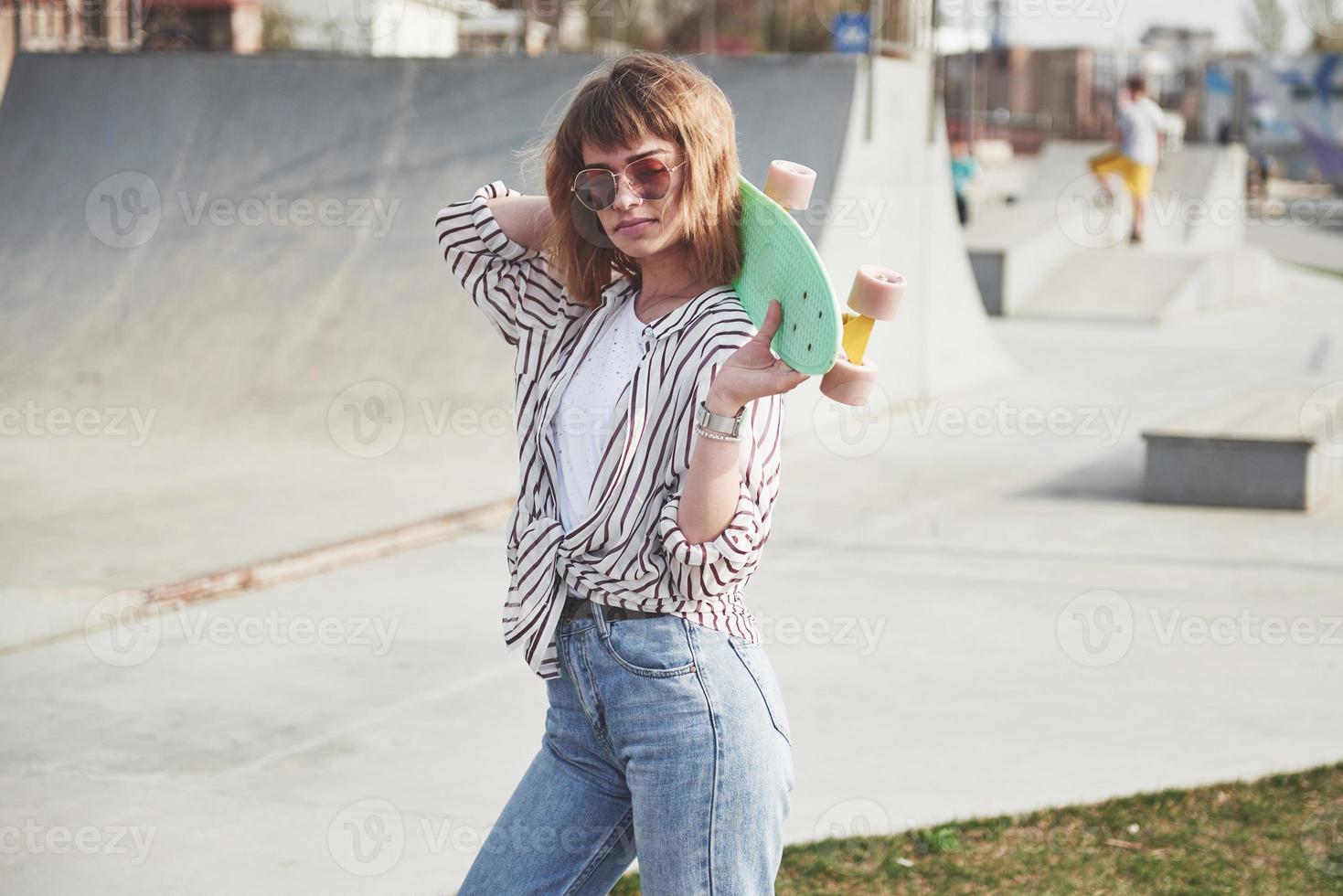 elegante y bella mujer joven con una patineta, en un hermoso día soleado de verano. foto