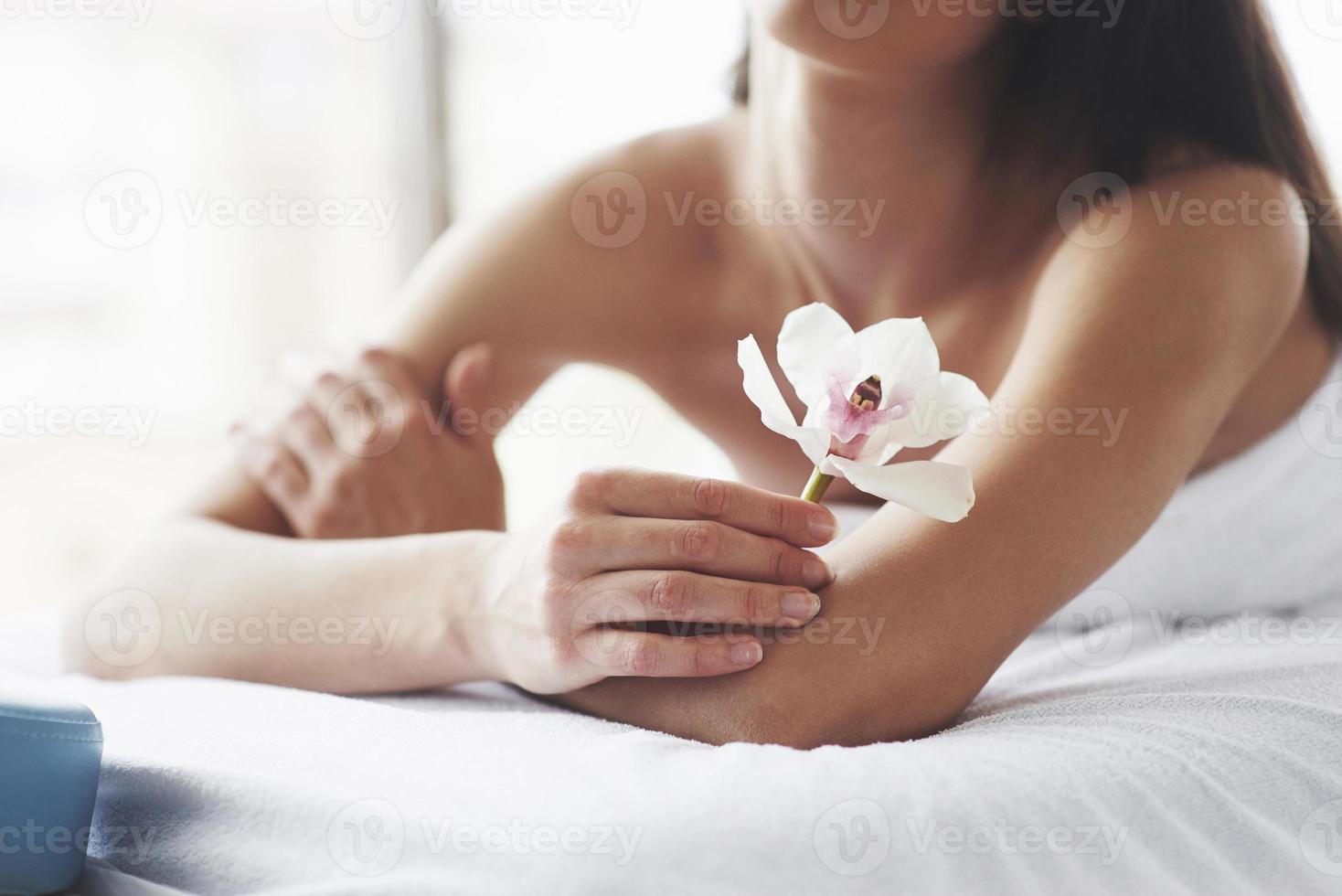 mujer de hermoso cuerpo con orquídea de flor blanca y cuidado del cuerpo. foto