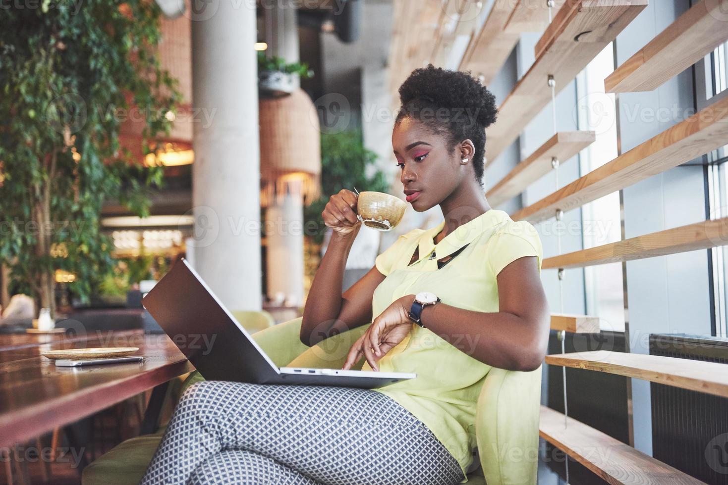 Beautiful young woman sitting in a cafe and working on a laptop photo