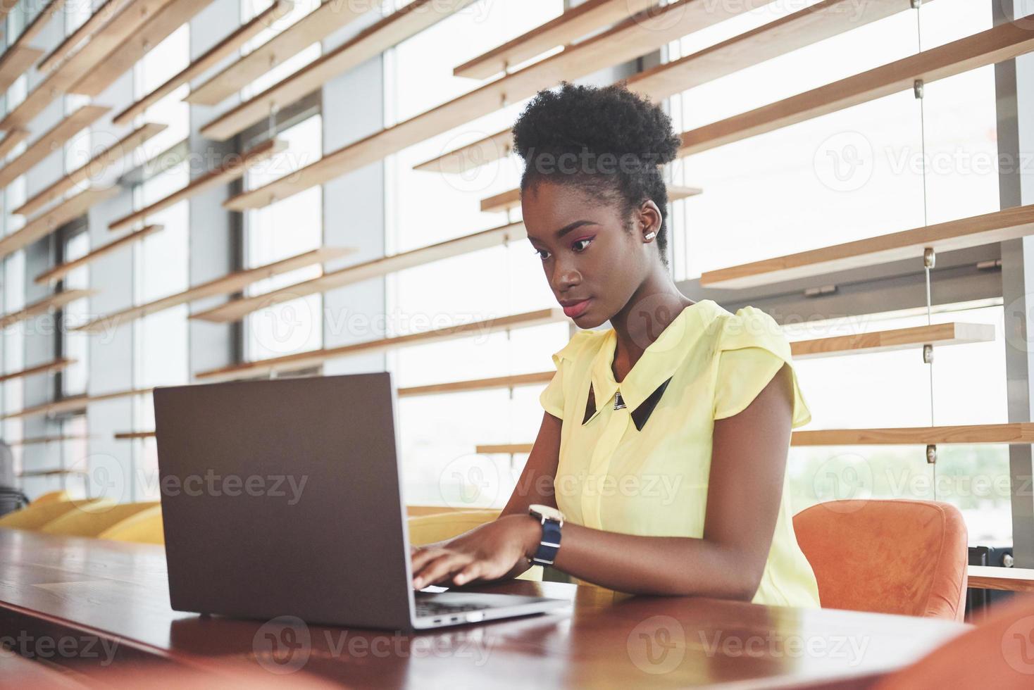 Beautiful young woman sitting in a cafe and working on a laptop photo