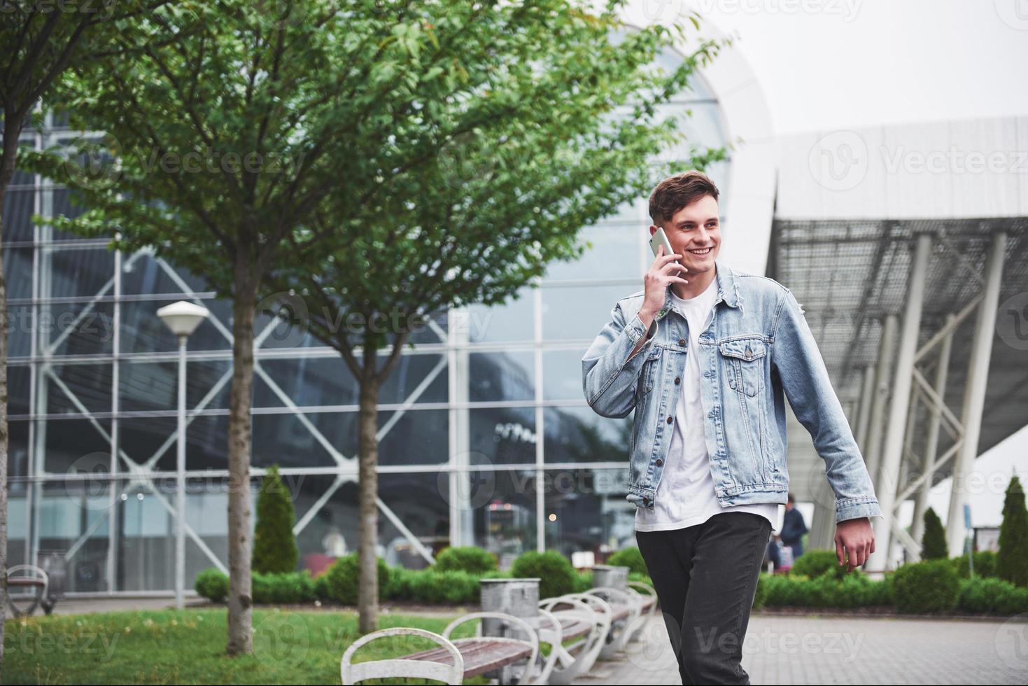 A handsome young man talking on the phone near the office space. photo