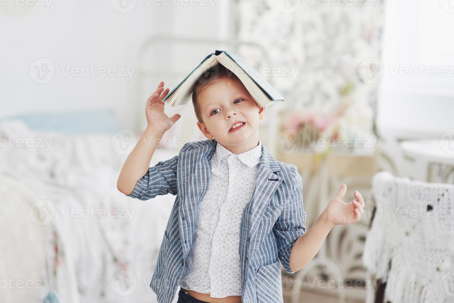 foto de colegial diligente con el libro en la cabeza haciendo los deberes. el colegial está cansado de hacer los deberes