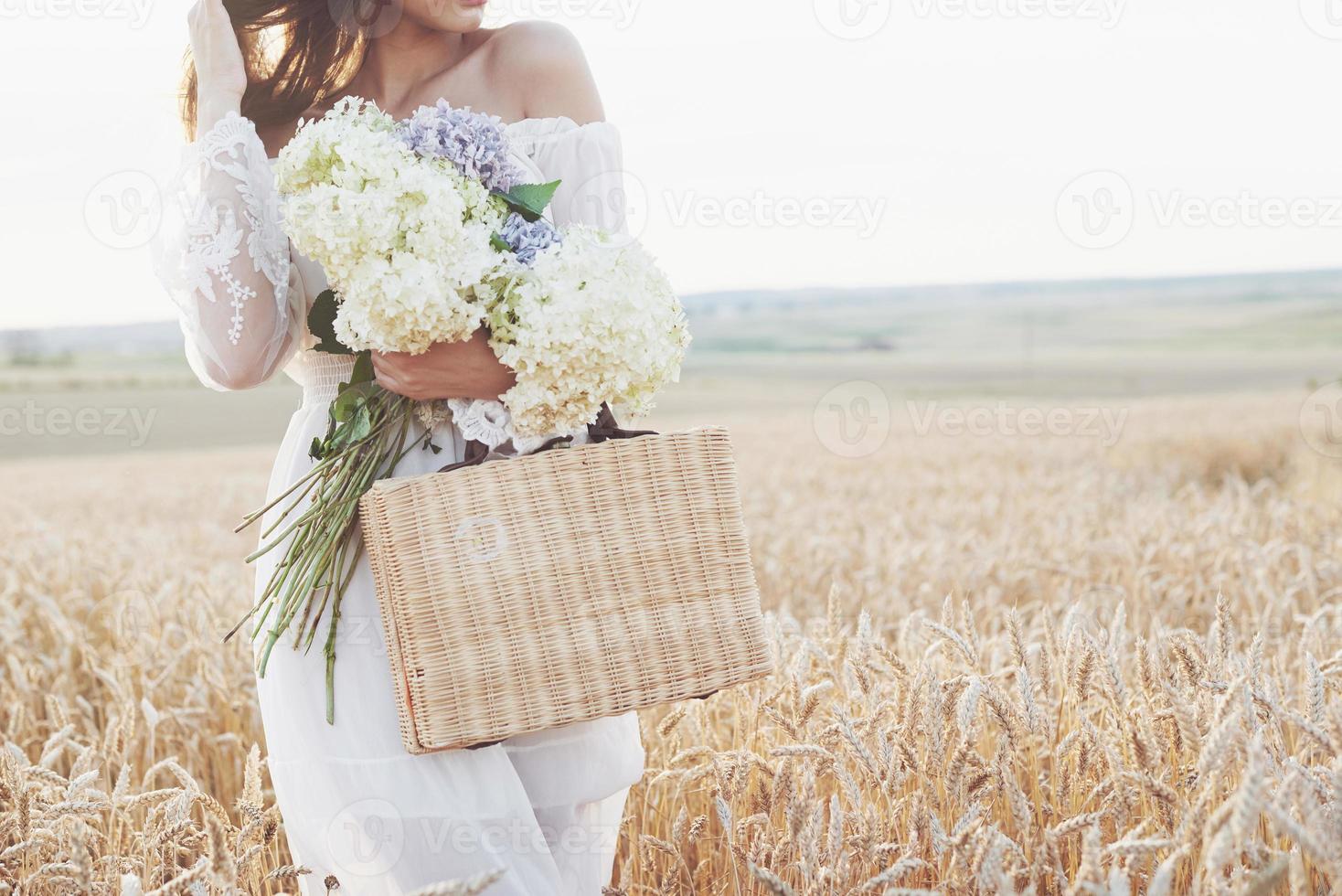 Beautiful girl in white dress running on the autumn field of wheat at sunset time photo