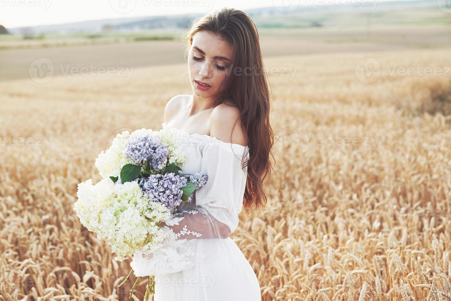 Beautiful girl in white dress running on the autumn field of wheat at sunset time photo