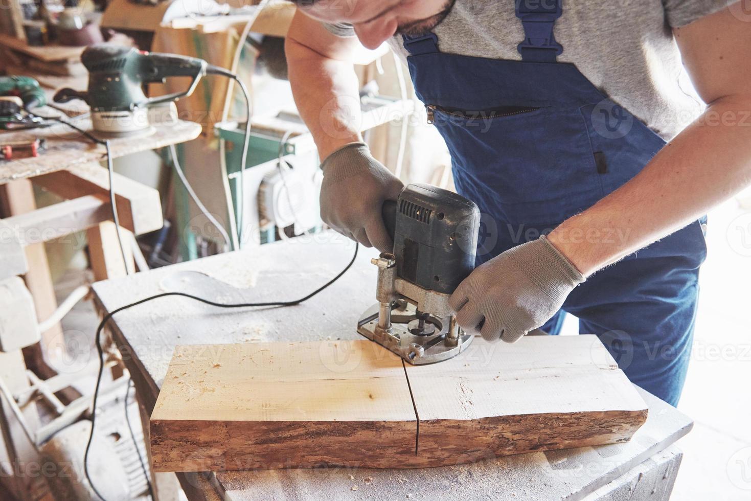 Portrait of a carpenter in working clothes in the workshop of the joiner's shop. photo