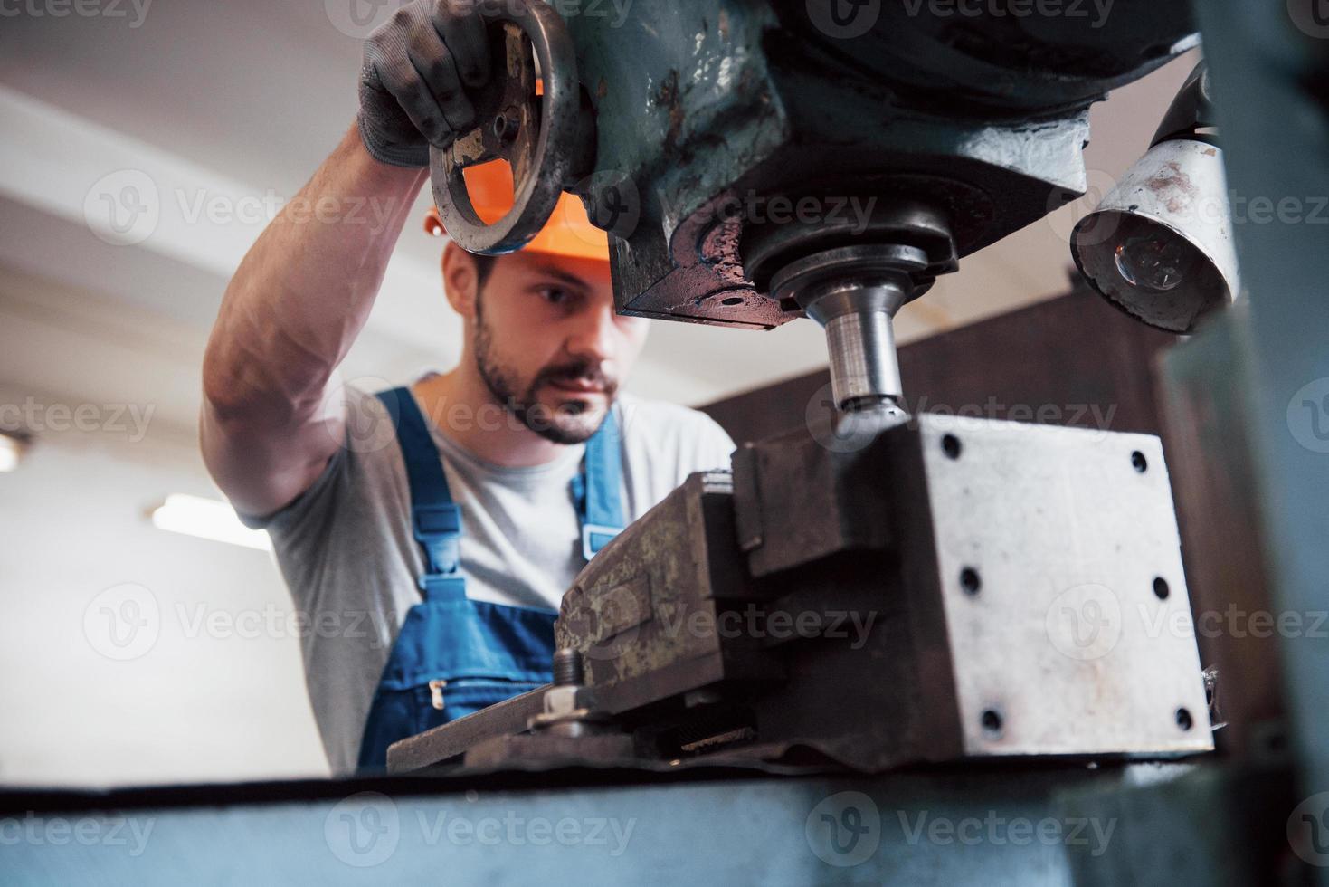 retrato de un joven trabajador con casco en una gran fábrica de reciclaje de residuos. el ingeniero supervisa el trabajo de las máquinas y otros equipos foto