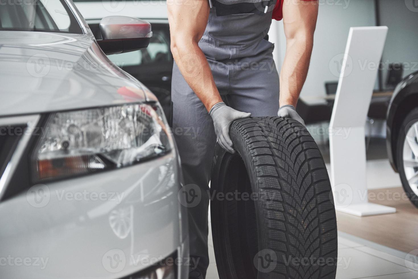 Mechanic holding a tire tire at the repair garage. replacement of winter and summer tires photo