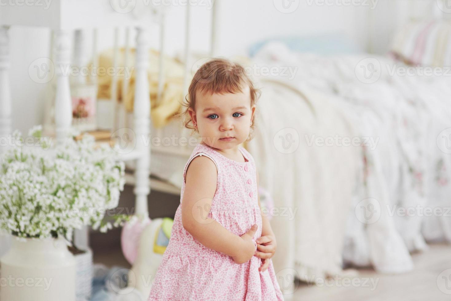 Beautiful little girl playing toys. Blue-eyed blonde. White chair. Children's room. Happy small girl portrait. Childhood concept photo