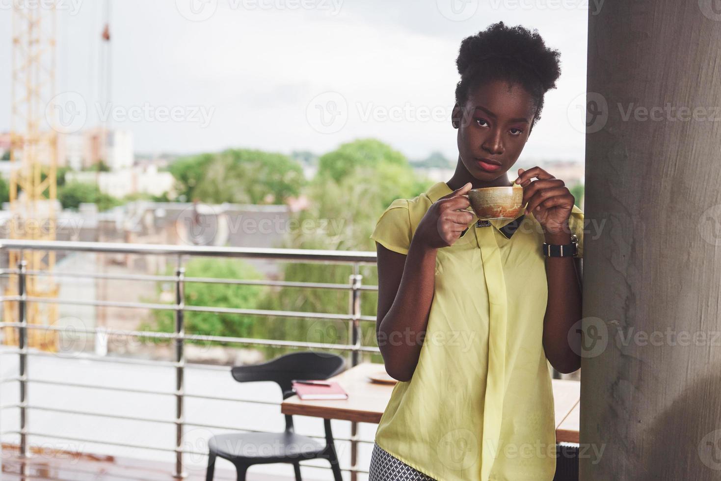 joven y bella mujer de negocios afroamericana tomando café en un café. hermoso lugar acogedor foto