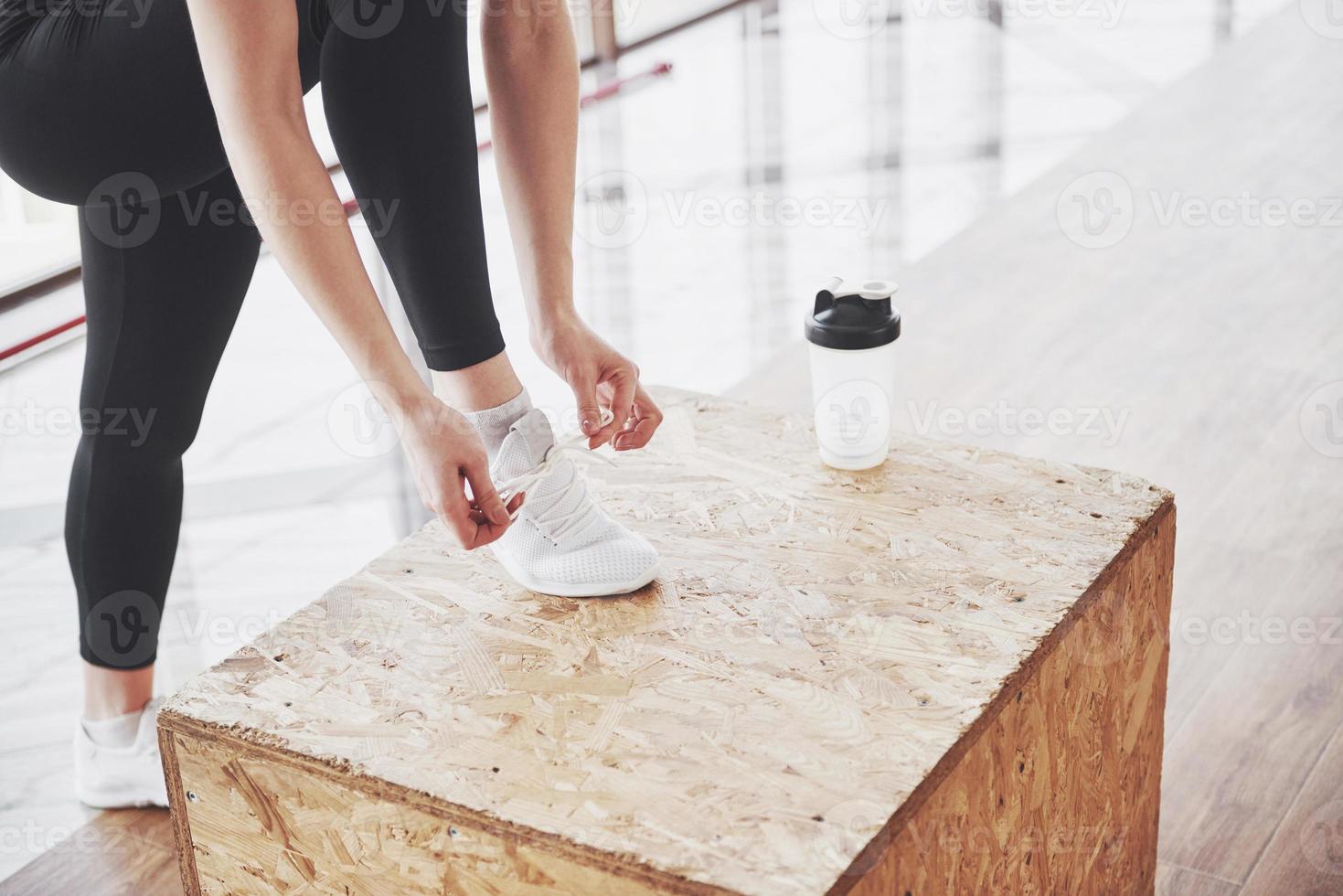 relajante después del entrenamiento. Vista de la joven y bella mujer mirando a otro lado mientras está sentado en la colchoneta de ejercicios en el gimnasio foto