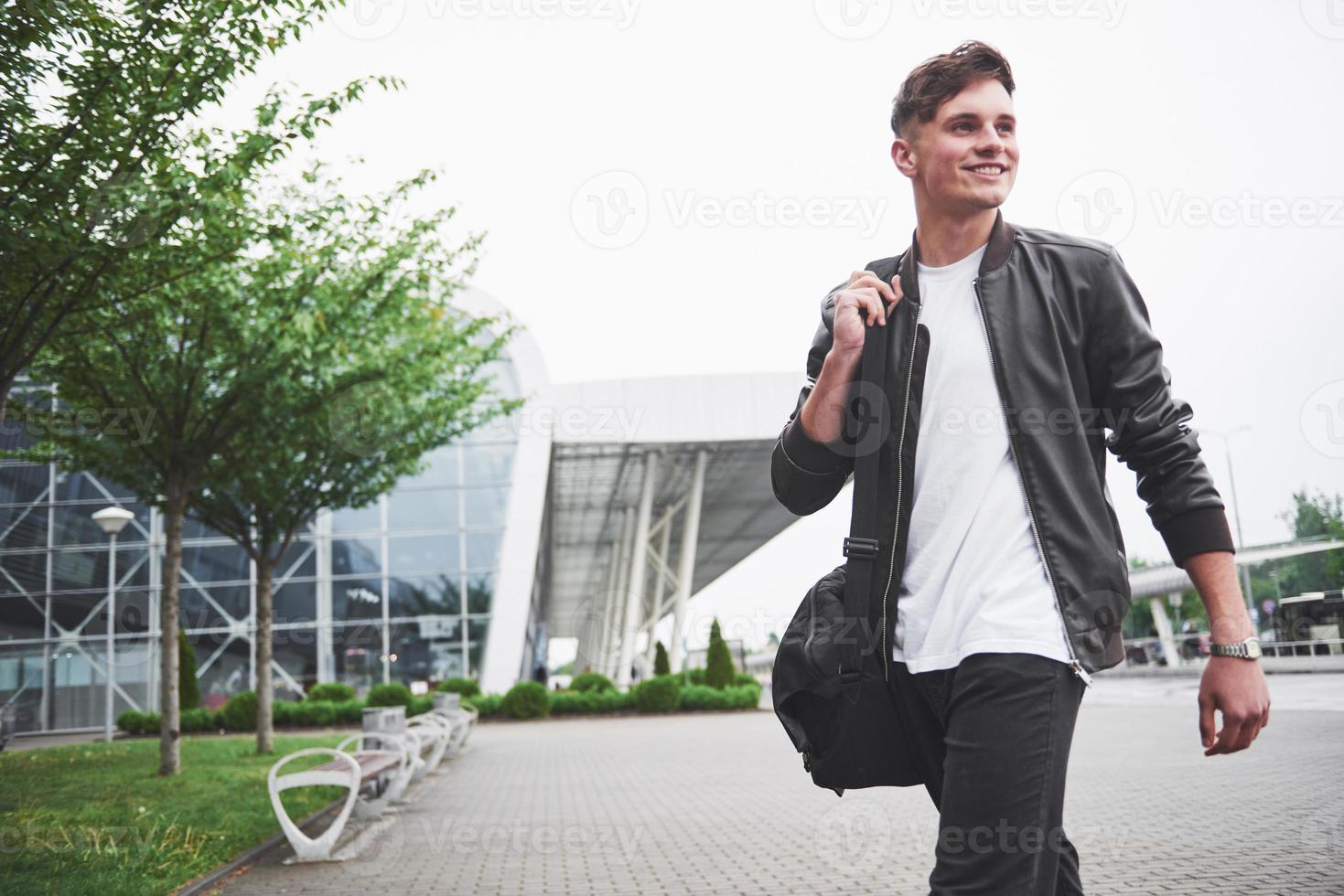 Young handsome man with a bag on his shoulder in a hurry to the airport. photo