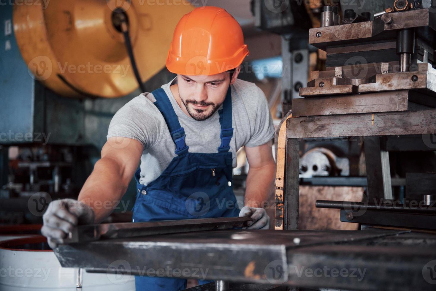 retrato de un joven trabajador con casco en una gran fábrica de reciclaje de residuos. el ingeniero supervisa el trabajo de las máquinas y otros equipos foto