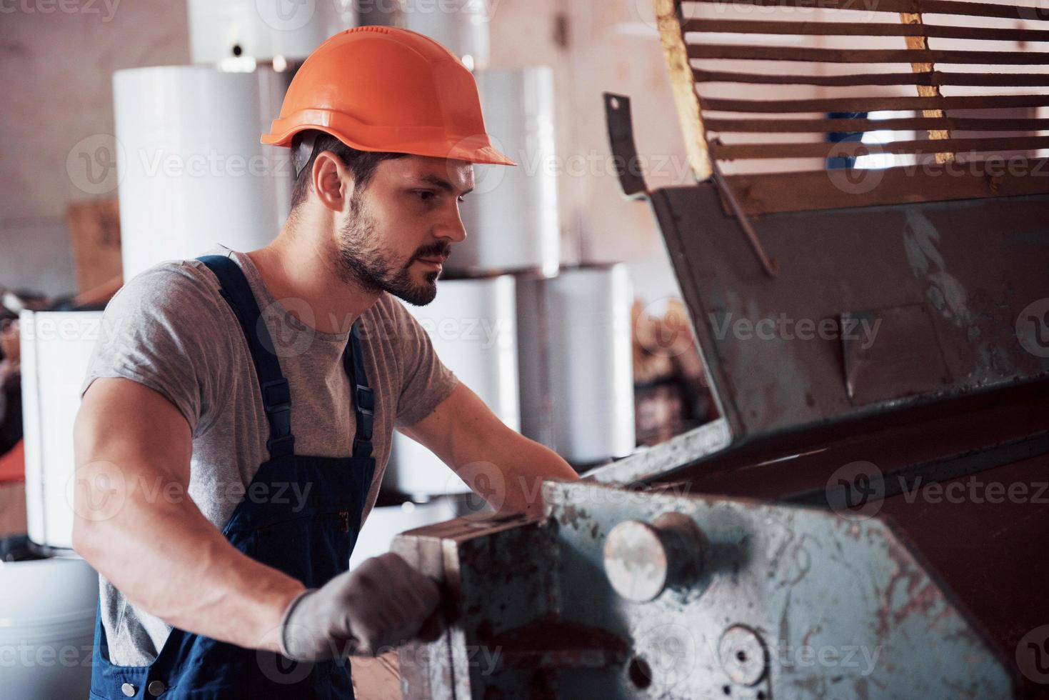 Portrait of a young worker in a hard hat at a large waste recycling factory. The engineer monitors the work of machines and other equipment photo