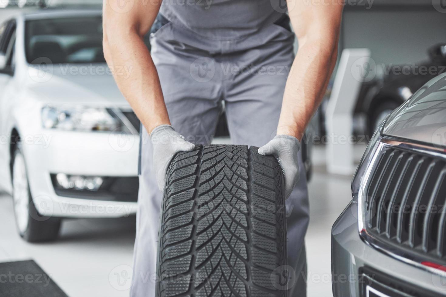 Mechanic holding a tire tire at the repair garage. replacement of winter and summer tires photo