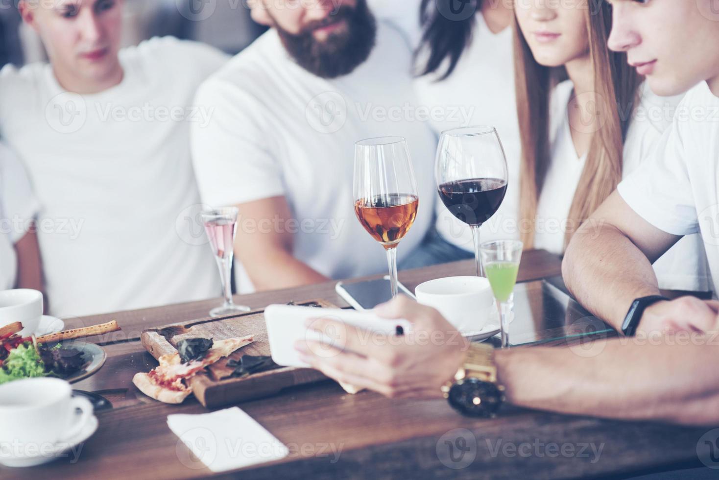 un grupo de personas hace una foto selfie en un café. los mejores amigos se reunieron en una mesa para cenar comiendo pizza y cantando varias bebidas