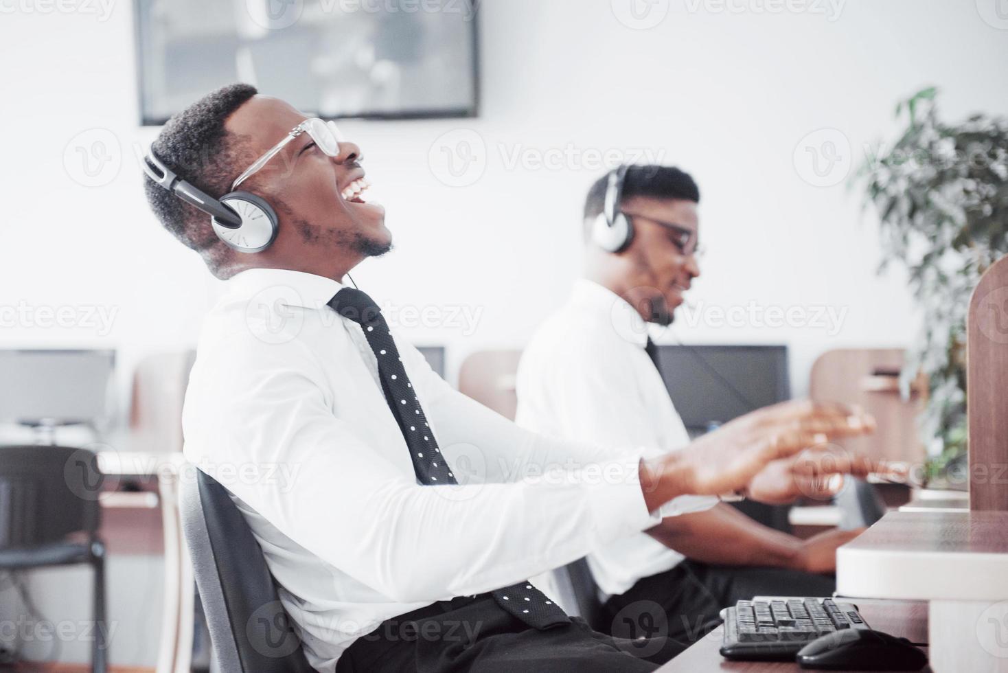 Operador de soporte al cliente afroamericano con auriculares manos libres trabajando en la oficina foto