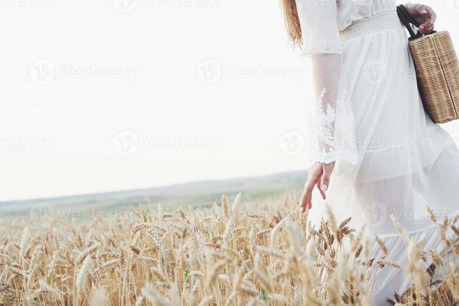 Young sensitive girl in white dress posing in a field of golden wheat photo