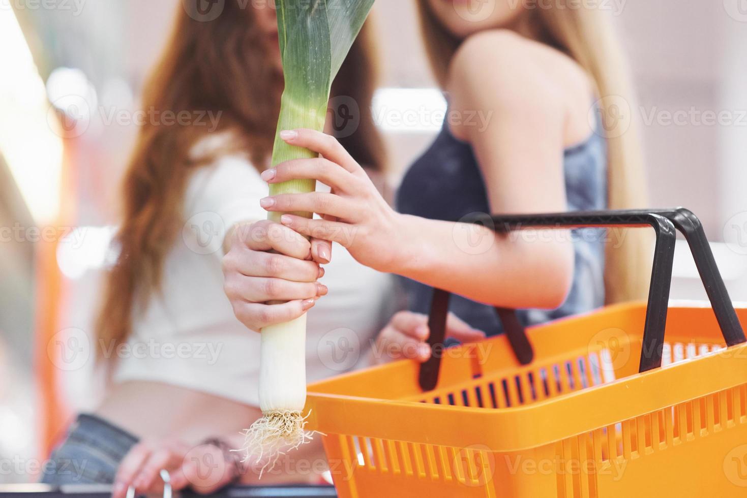 Two women choose seasonal vegetables in the supermarket grocery store. photo