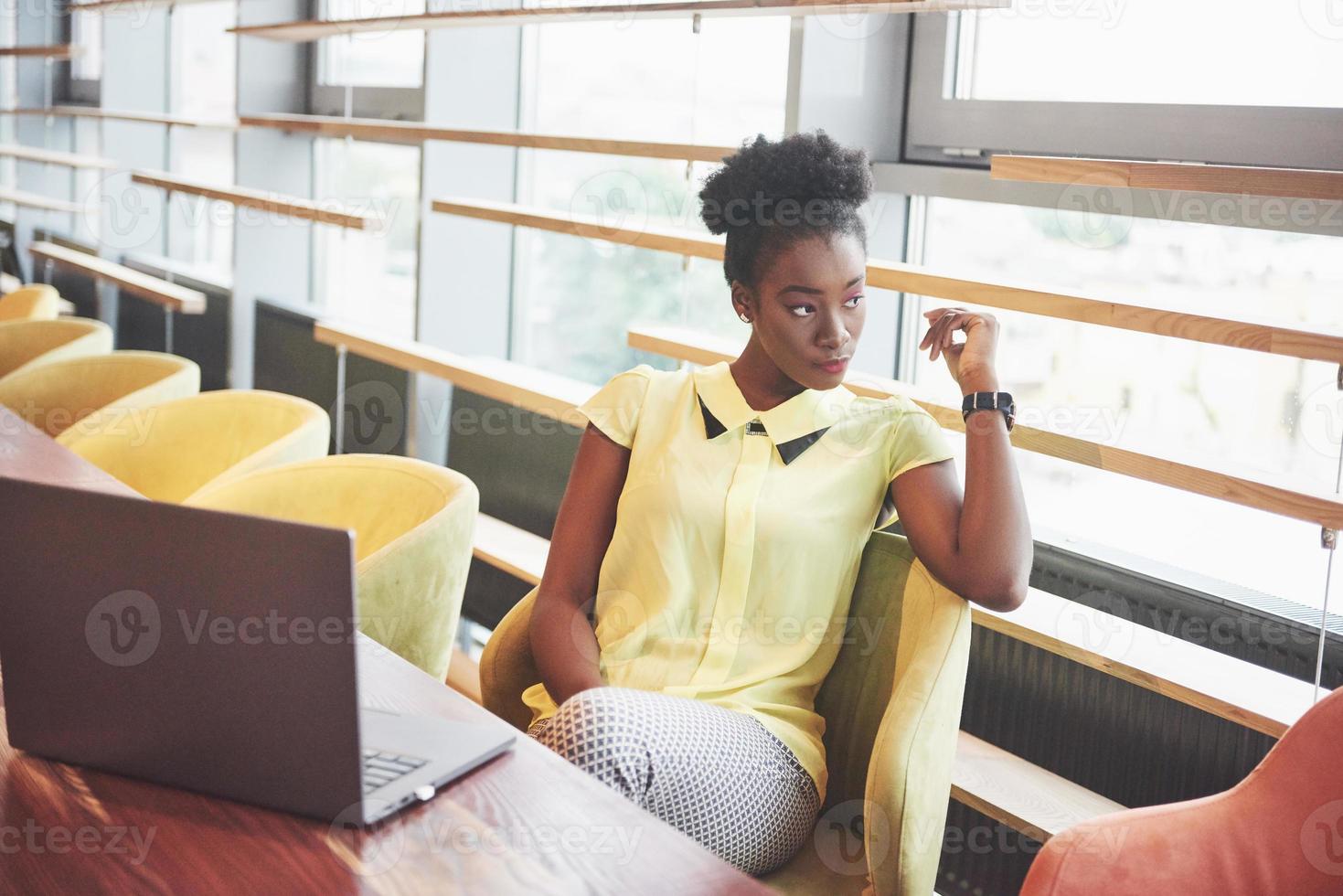 joven afroamericana con cabello rizado oscuro pensativo en un café. foto