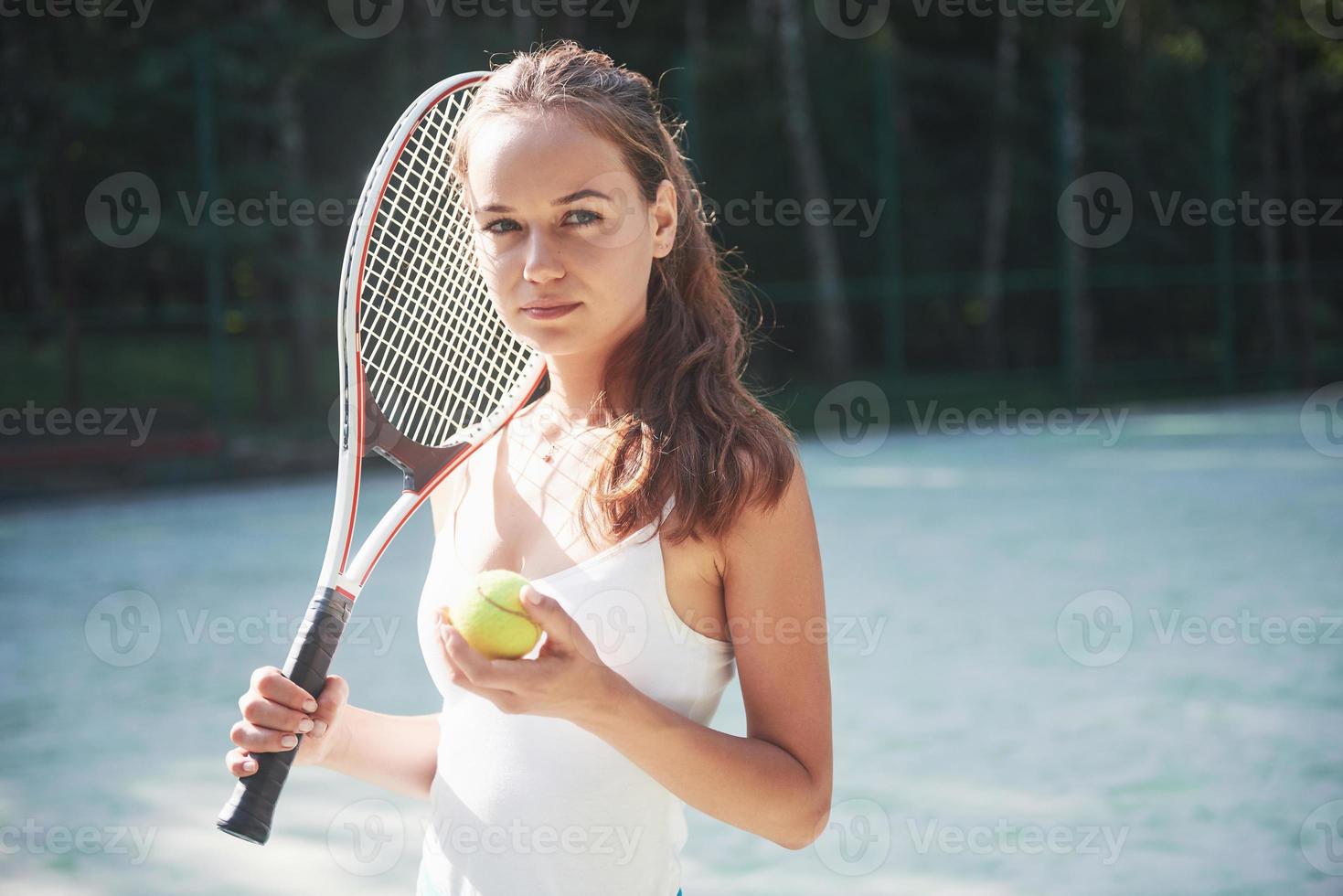 Una mujer bonita vistiendo una cancha de tenis de ropa deportiva en la cancha foto