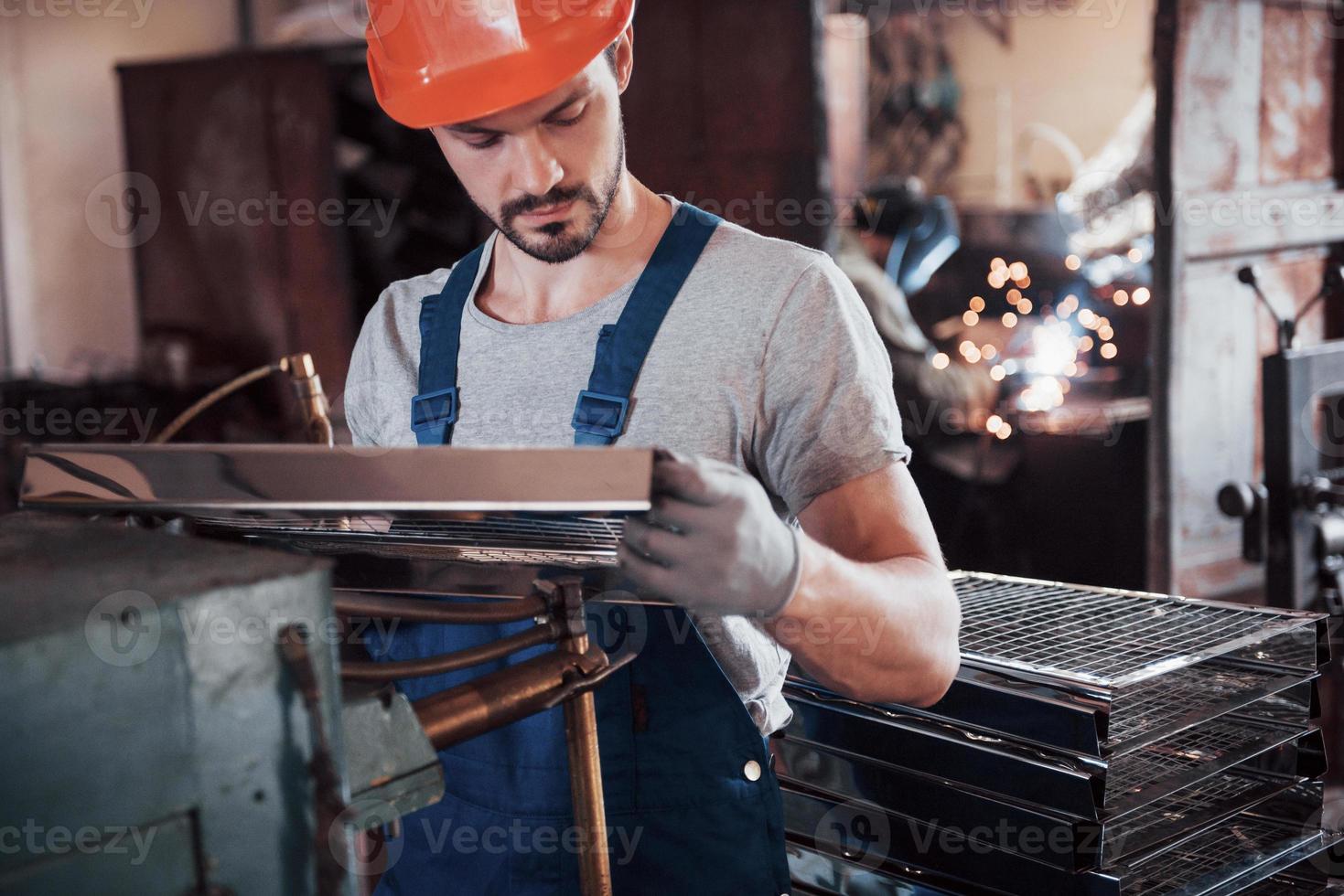 Portrait of a young worker in a hard hat at a large waste recycling factory. The engineer monitors the work of machines and other equipment photo