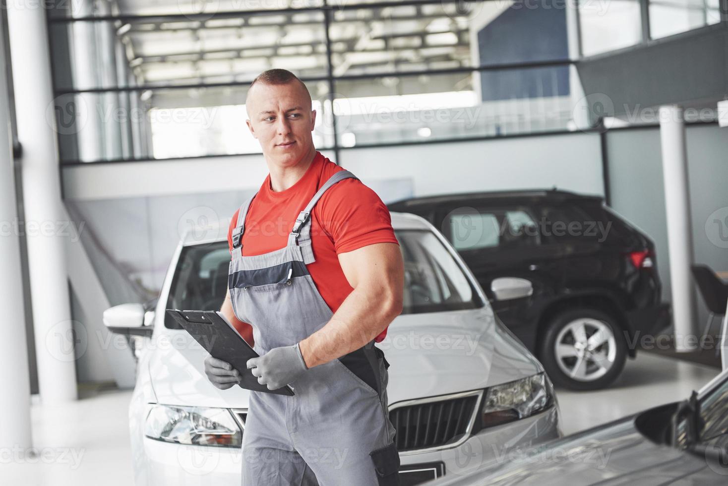 A handsome young man speaks at a car dealership, repairing a car in a workshop. photo