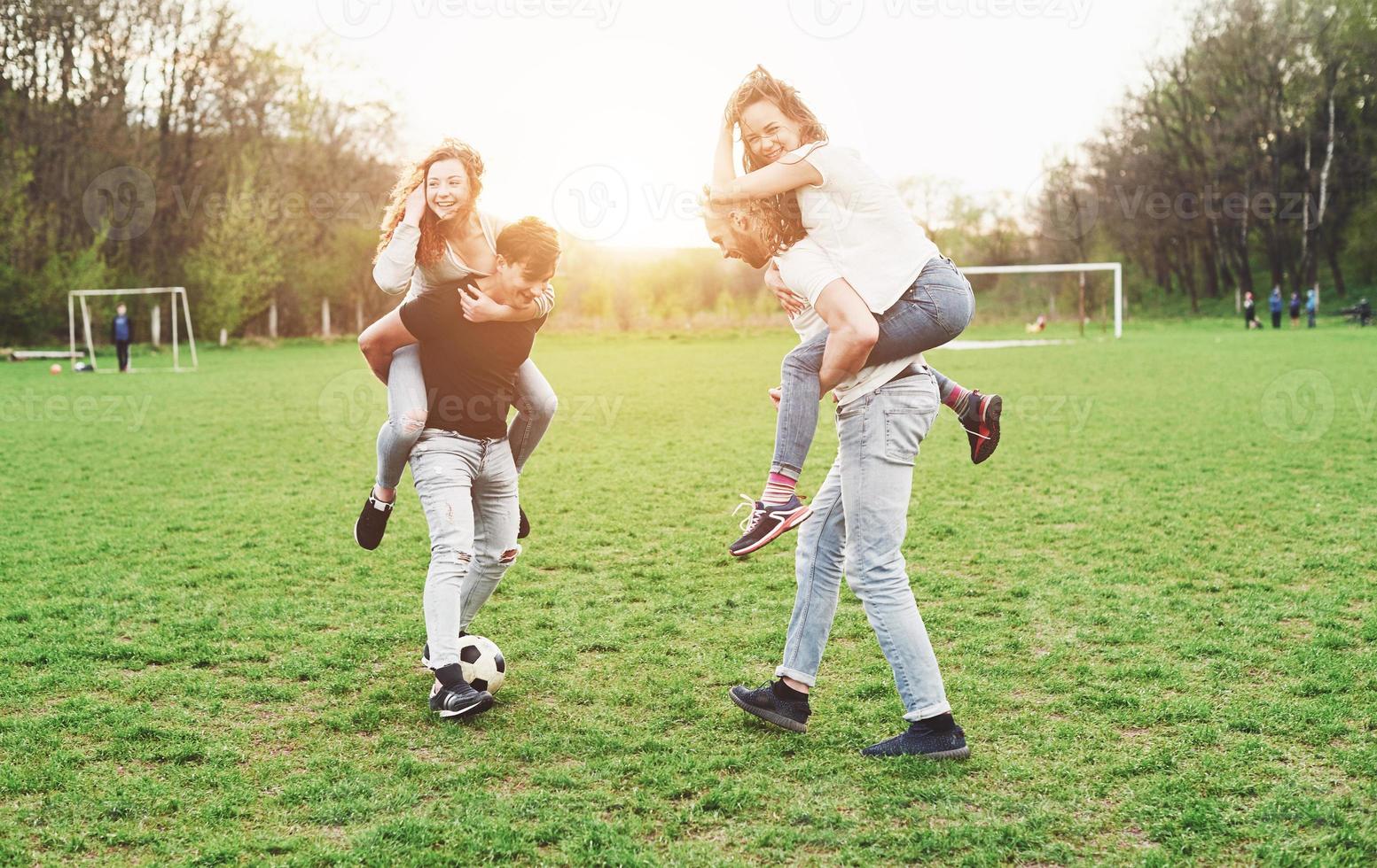 un grupo de amigos en ropa casual juega al fútbol al aire libre. la gente se divierte y se divierte. descanso activo y puesta de sol escénica. foto