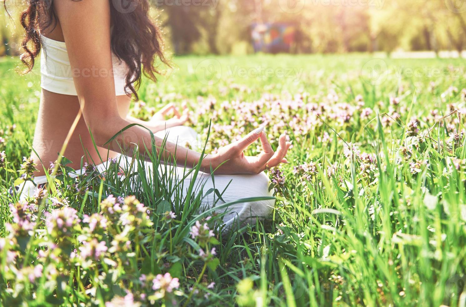 La meditación del yoga en un parque sobre el césped es una mujer sana en reposo foto