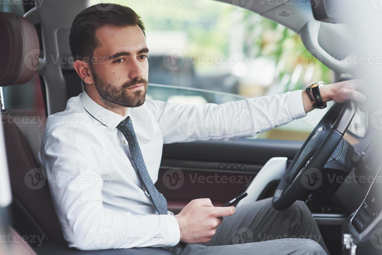 hermoso joven en traje completo mientras conduce un coche foto