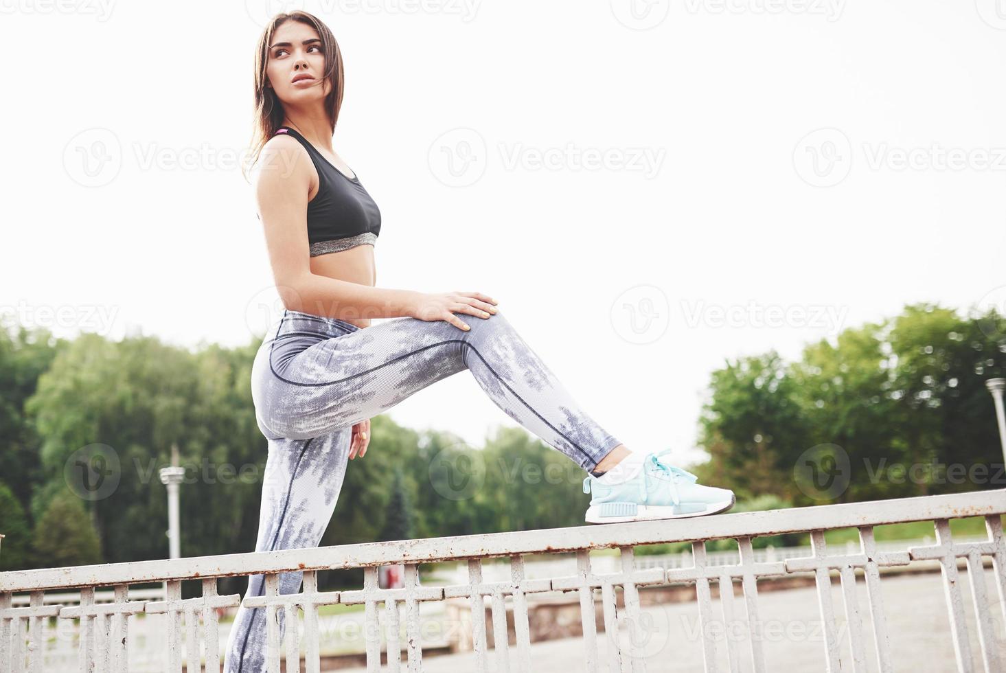 A beautiful athlete brunette performs outdoor exercises photo