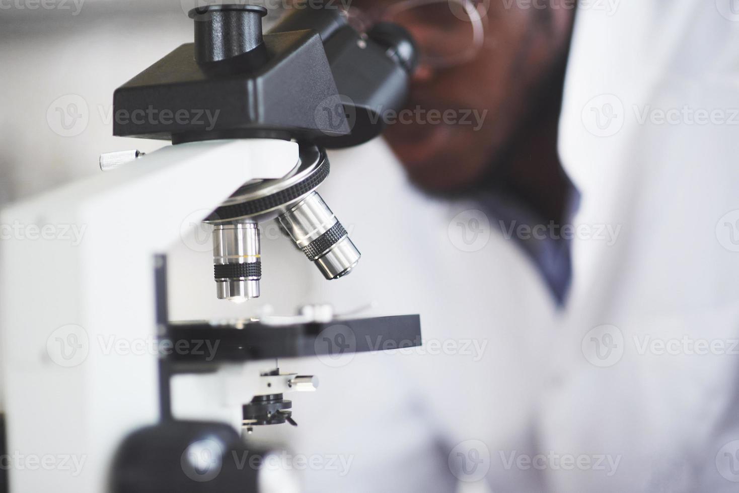 The scientist works with a microscope in a laboratory conducting experiments and formulas. photo