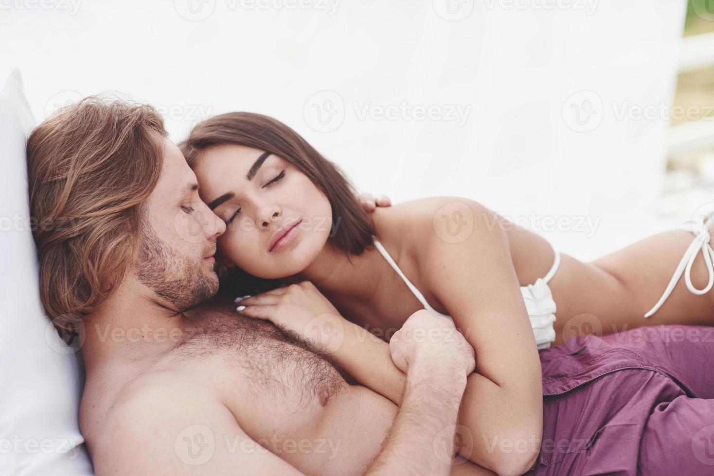 A beautiful couple relaxing on the sandy beach, wearing bathing clothes. Romantic atmosphere. photo