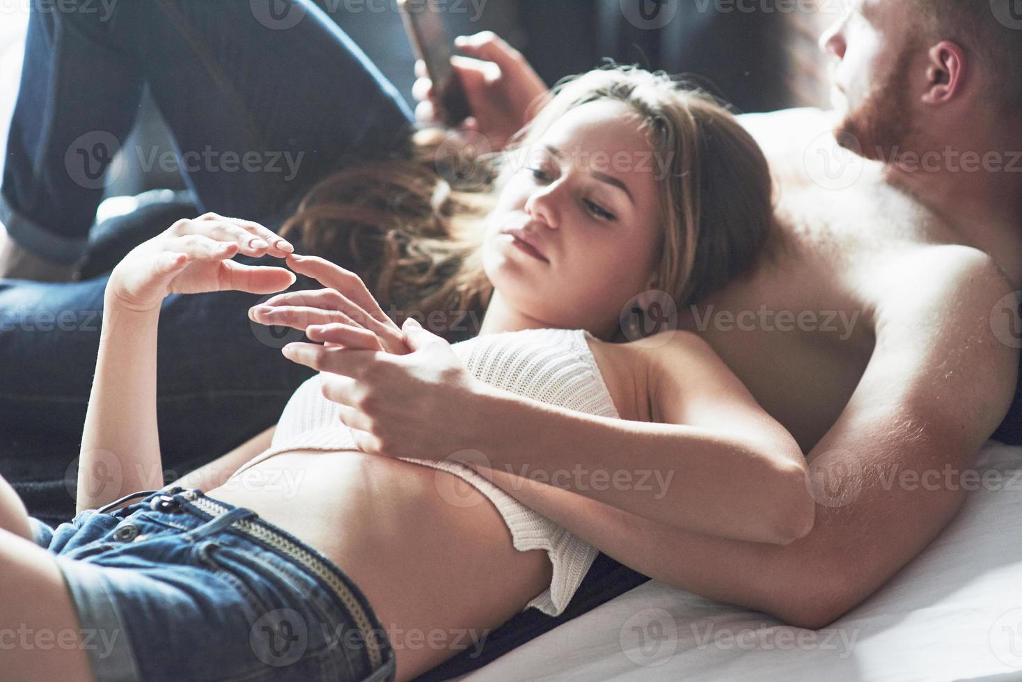 Los amantes jóvenes atractivos tienen parejas jugando juntos en la cama, vistiendo lencería sexy en una habitación de hotel. foto