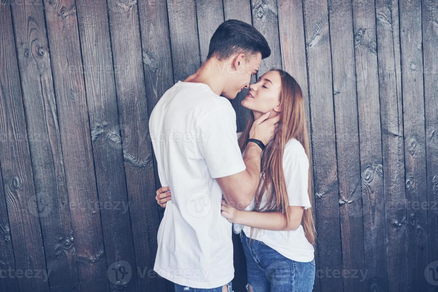 Young couple, guy and girl together on a wooden wall background. They are happy together and dressed alike. Always in a trend photo