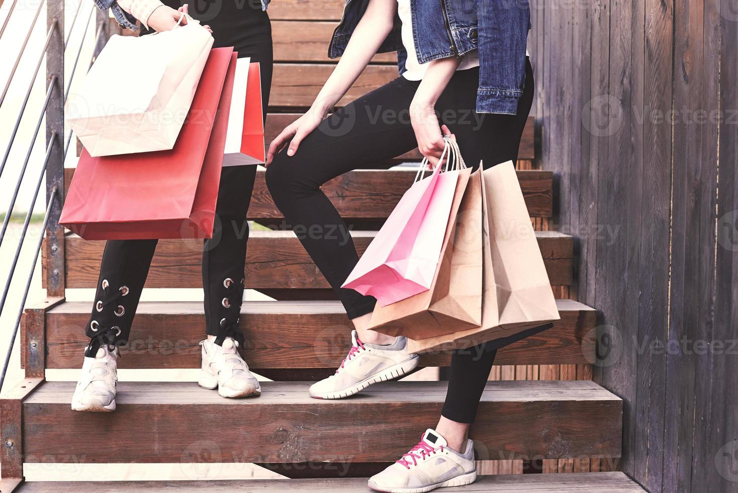 Dos joven llevando bolsas de la compra mientras caminaba por las escaleras después de visitar las tiendas foto