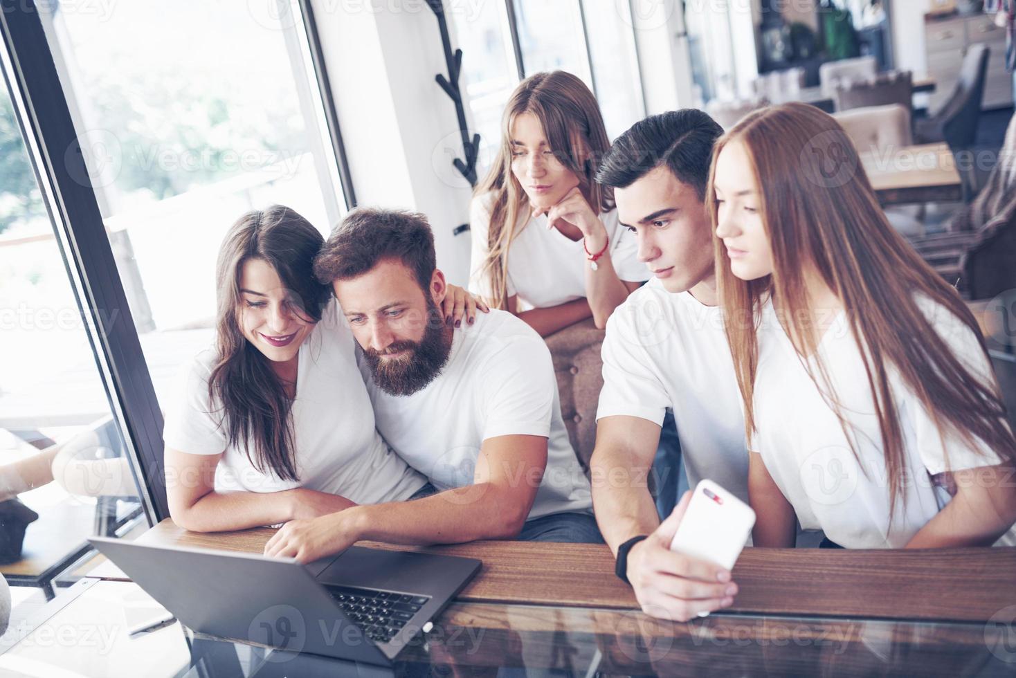 A group of young people with gadgets and a laptop arrange a brainstorm and communicate with each other. The concept of developing a young business photo