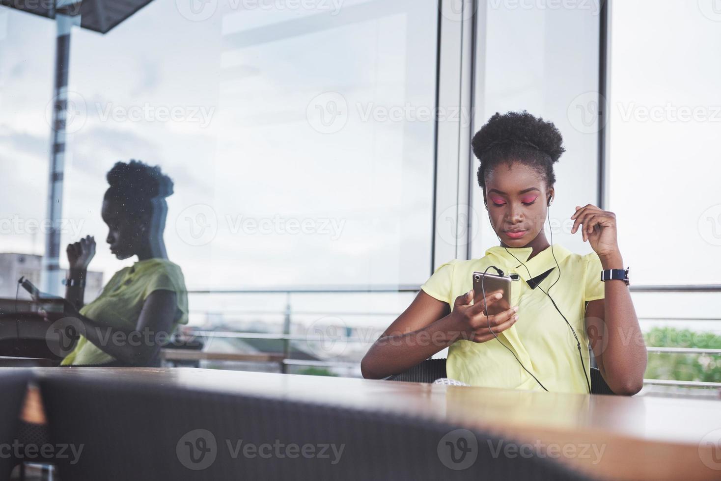 retrato de una atractiva joven negra con un teléfono móvil en un café. foto