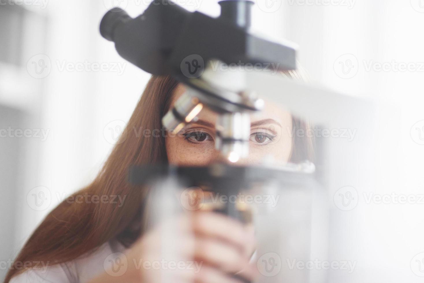 asistente de laboratorio con microscopio bombilla de cristalería de laboratorio con productos químicos. foto