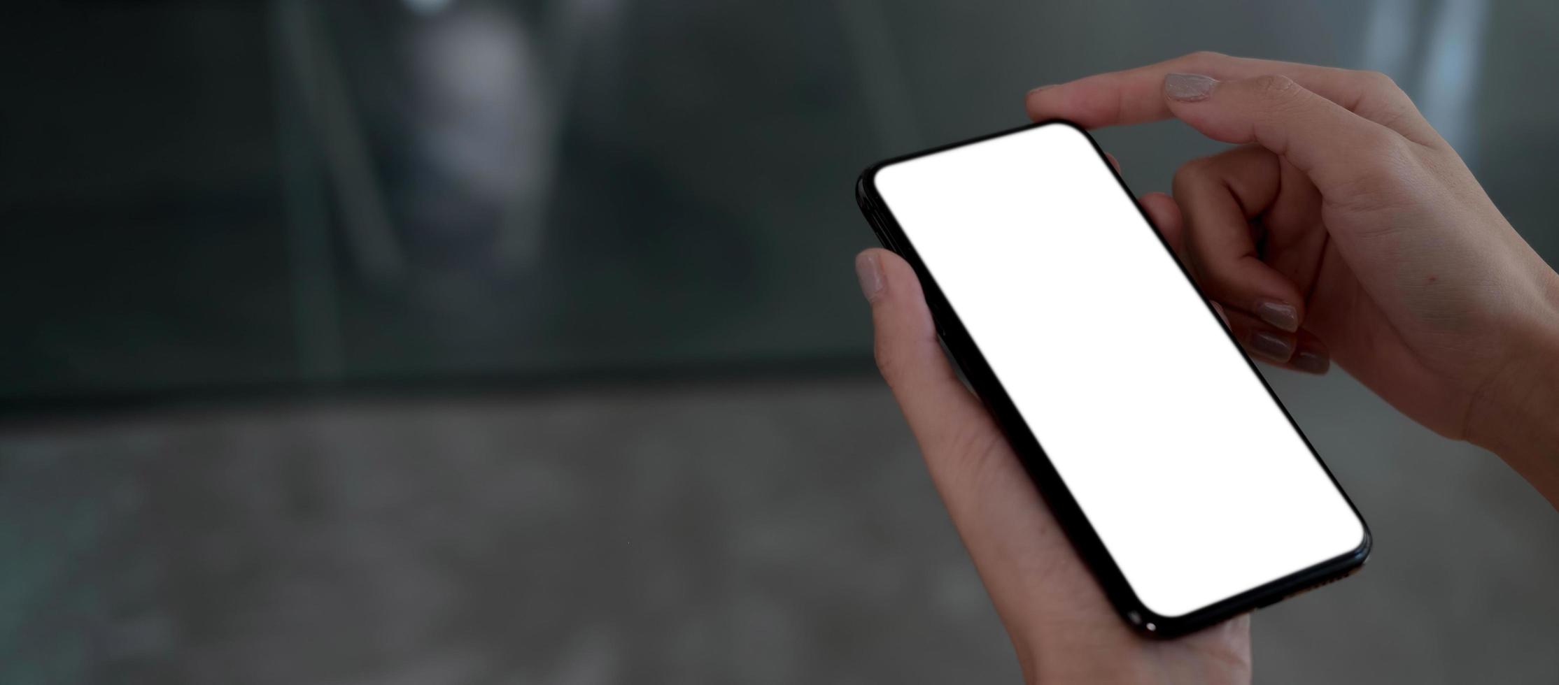 Mockup image blank white screen cell phone.women hand holding texting using mobile on desk at home office. photo