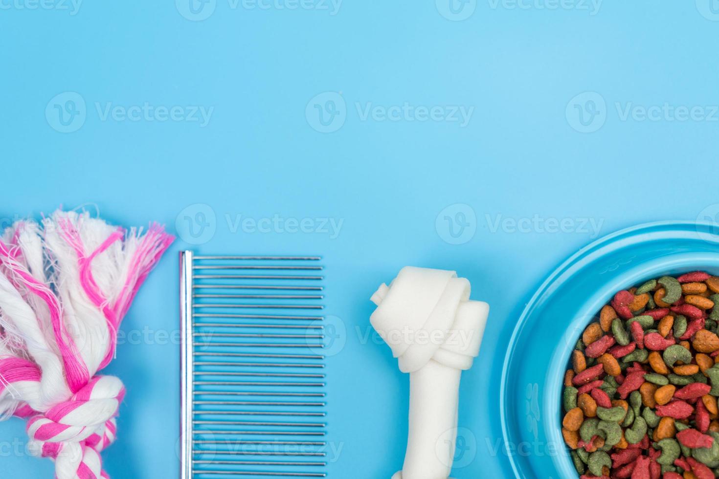 Dry food in bowls with bone, toy, for pets on color background photo