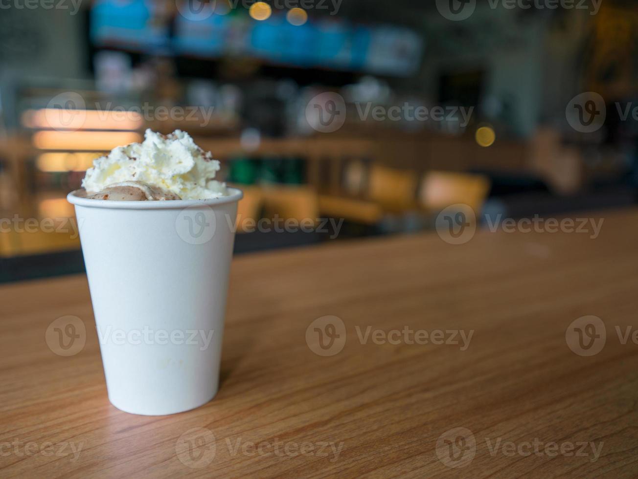 Hot mocha with whipping cream in paper cup on wooden table photo