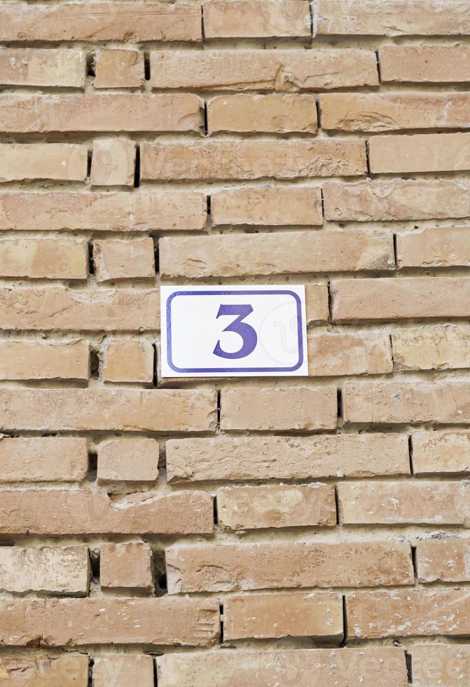 Number three on a brick wall photo