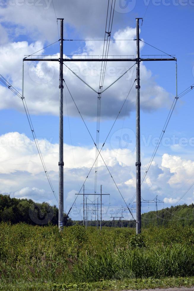 The high voltage line is in the field. Electric pole energized. Power line. photo