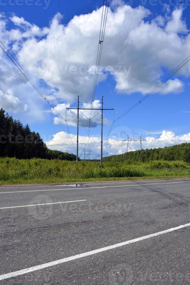 una línea de alta tensión atraviesa la vía. poste eléctrico energizado. foto vertical.