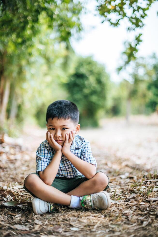 niño feliz sentado y pensando solo en el parque foto