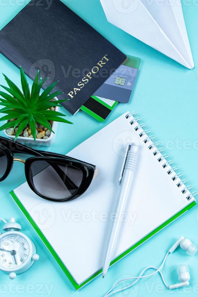 Vacation planning. Travel accessories on a blue background. Passport, sunglasses and notepad. photo