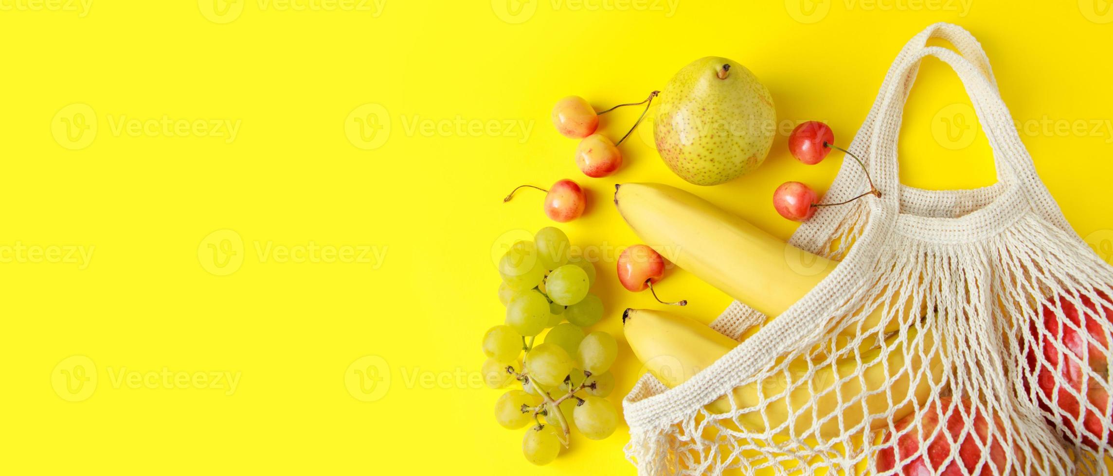 frutas maduras en bolsa de malla sobre fondo amarillo. bolsa de hilo de algodón ecológico para ir de compras. alimentos veganos dietéticos orgánicos. formato de banner. foto