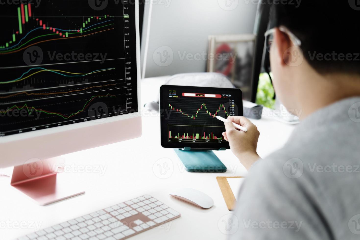 Investment professionals point their pen at their computer monitor to analyze the stock market for profit. photo